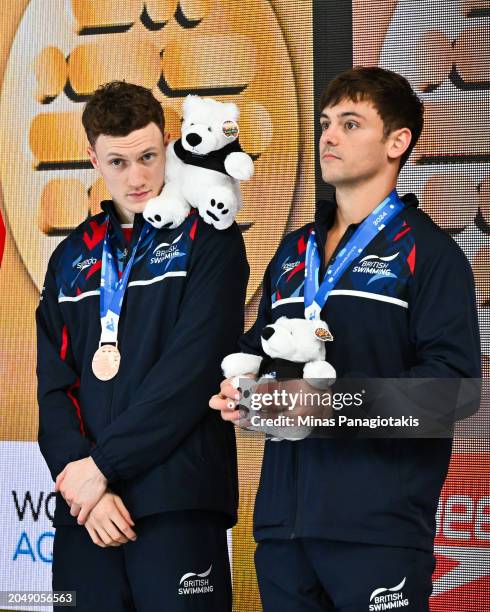 Noah Williams of Great Britain puts a stuffy toy on his shoulder as teammate Thomas Daley looks on from the podium after finishing third in the Men's...