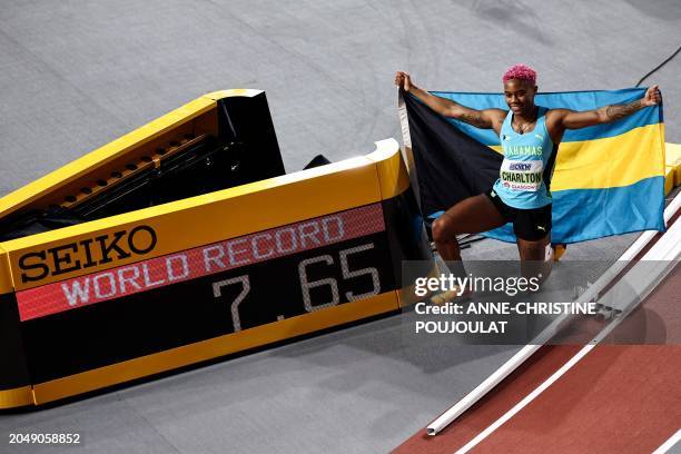 First-placed Bahamas' Devynne Charlton poses next to the score board reading her world record after winning the Women's 60m hurdles final during the...