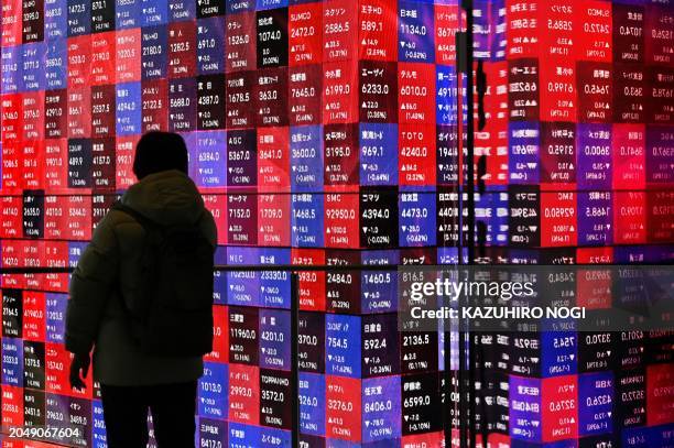 Man looks at an electronic boards displaying stock prices of companies listed on the Tokyo Stock Exchange in Tokyo on March 4, 2024.