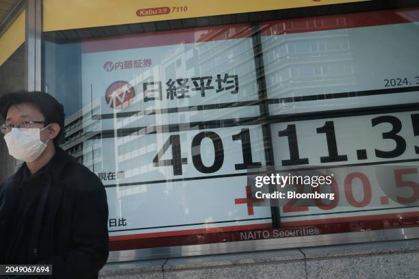 Pedestrian in front of an electronic stock board showing the Nikkei 225 Stock Average outside a securities firm in Tokyo, Japan, on Monday, March 4,...