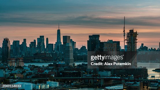 New building construction in Greenpoint, Brooklyn at sunset with Newtown Creec flowing into the East River. Distant view of Manhattan with visible Freedom Tower.