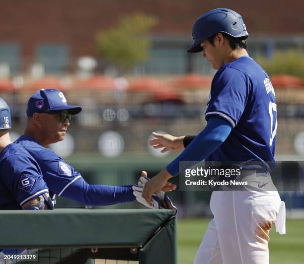Shohei Ohtani of the Los Angeles Dodgers is greeted by manager Dave Roberts after scoring on a sacrifice fly by Will Smith in the first inning of a...