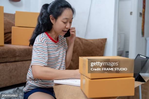 the asian woman meticulously arranges her selling packaging, preparing for a day of shopping and fulfilling orders for her exquisite merchandise. - fulfilling online orders stock pictures, royalty-free photos & images