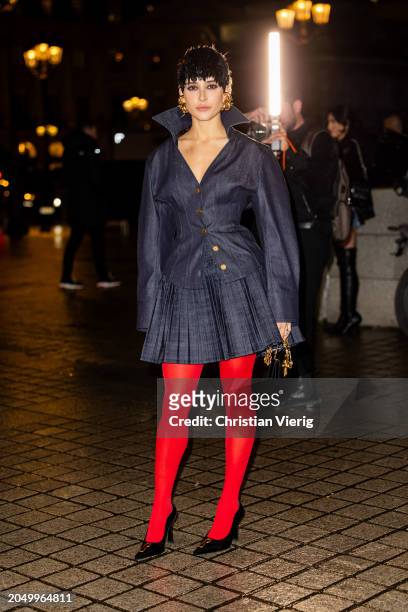 Livia Nunes Marques wears red tights, navy pleated skirt, button up jacket outside Schiaparelli during the Womenswear Fall/Winter 2024/2025 as part...