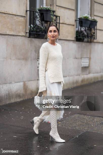 Geraldine Boublil wears creme white sweater, asymmetric fringed white skirt, bag, knee high boots outside Paco Rabanne during the Womenswear...