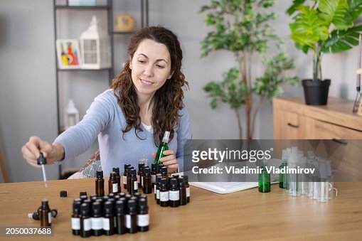 Woman Sitting at Table With Bottles of Essential Oils
