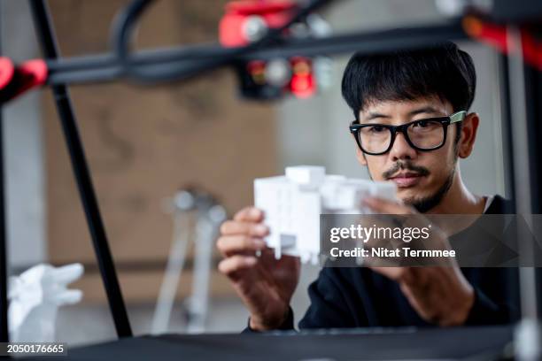 3d printing can help make construction sustainable in your project. a male construction designer reviews an architectural model prototype printed by a 3d printer machine at an architect's office. - designer industriale foto e immagini stock