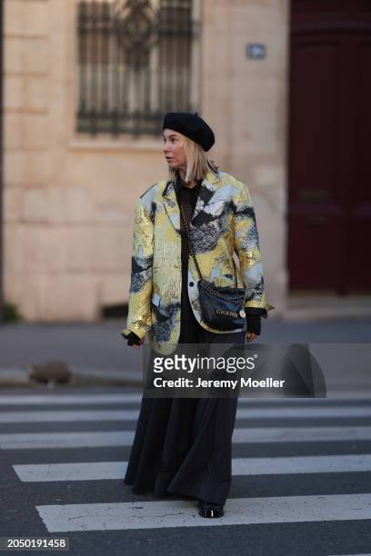 Karin Teigl seen wearing H&M black baret hat, H&M Studios black blouse / shirt, Stine Goya blue / green metallic print pattern blazer jacket, H&M...
