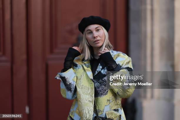 Karin Teigl seen wearing H&M black baret hat, H&M Studios black blouse / shirt, Stine Goya blue / green metallic print pattern blazer jacket, during...