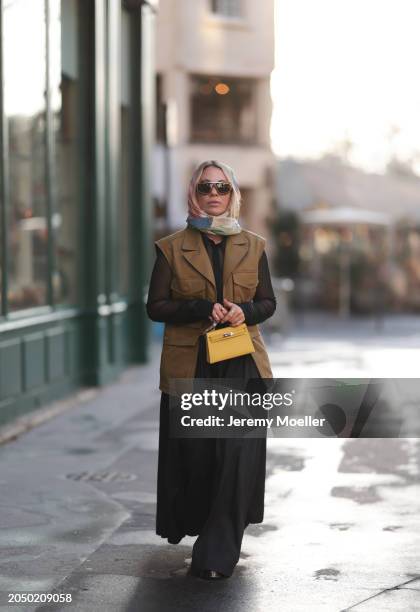 Karin Teigl seen wearing Loewe gold / brown tortoise sunglasses, H&M Studios colorful silk scarf, H&M Studios black blouse / shirt, H&M Studios khaki...