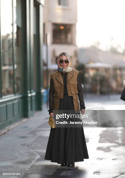 Karin Teigl seen wearing Loewe gold / brown tortoise sunglasses, H&M Studios colorful silk scarf, H&M Studios black blouse / shirt, H&M Studios khaki...