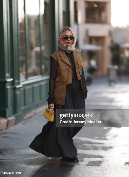 Karin Teigl seen wearing Loewe gold / brown tortoise sunglasses, H&M Studios colorful silk scarf, H&M Studios black blouse / shirt, H&M Studios khaki...