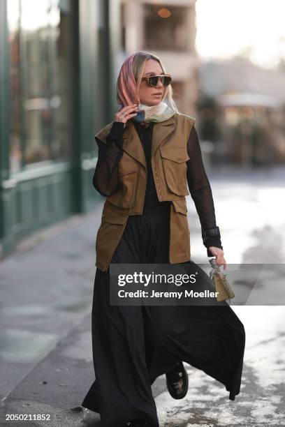 Karin Teigl seen wearing Loewe gold / brown tortoise sunglasses, H&M Studios colorful silk scarf, H&M Studios black blouse / shirt, H&M Studios khaki...