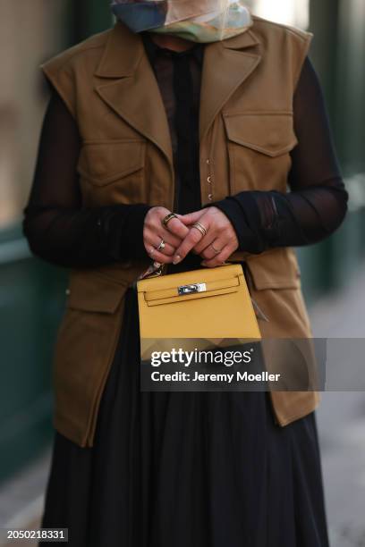 Karin Teigl seen wearing H&M Studios black blouse / shirt, H&M Studios khaki green utility gilet, gold rings, H&M Studios black oversized long maxi...