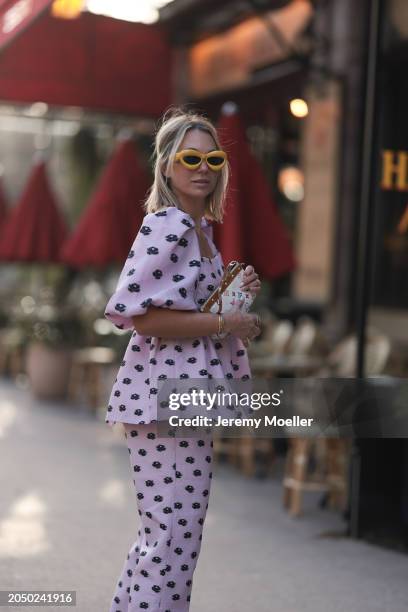 Karin Teigl seen wearing Loewe yellow sunglasses, gold necklaces, Stine Goya pink with black flower print pattern top with puffy sleeves, matching...