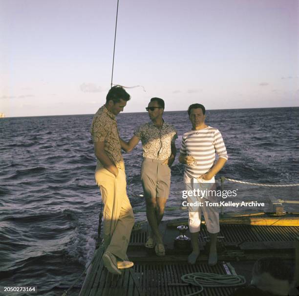 American basketball player Bud Palmer, wearing a patterned short-sleeve shirt and yellow trousers, American basketball player Bob Cousy, who wears a...