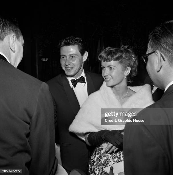 American actor and singer Eddie Fisher, wearing a tuxedo and bow tie, and his wife, American actress and singer Debbie Reynolds, who wears a white...