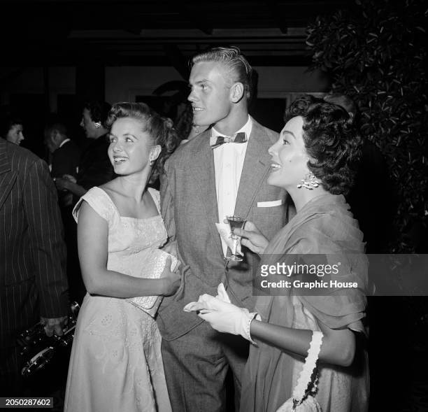 American actress and singer Debbie Reynolds, wearing a sleeveless white dress with a square neckline, American actor and singer Tab Hunter, who wears...