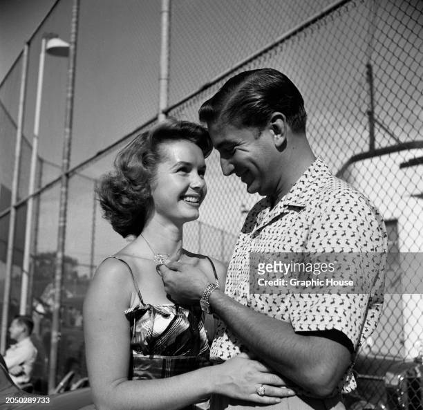American actress and singer Debbie Reynolds, wearing a dress with spaghetti straps, smiling as American businessman Bob Neal, who wears a...