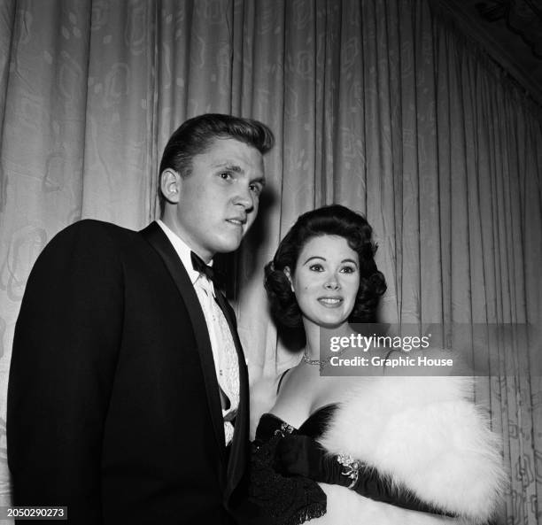 British-born American racing driver and entrepreneur Lance Reventlow, wearing a tuxedo and bow tie, with his wife, American actress Jill St John, who...