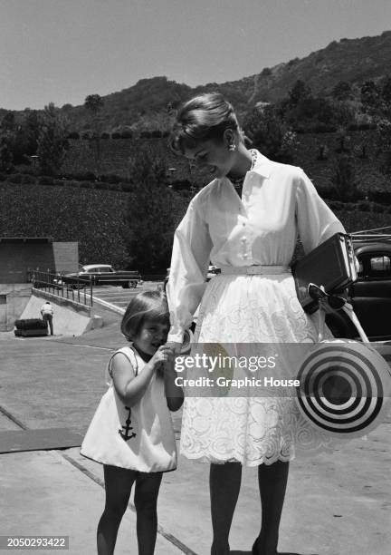 American actress and singer Debbie Reynolds holding the hand of her daughter, Carrie Fisher, as they attend a rehearsal for the Boys' Club of...