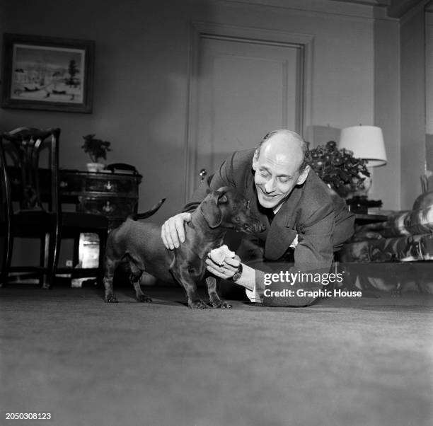 Austrian-born British opera impresario Rudolf Bing crouches beside his pet dachshund, Pip, at home in New York City, New York, 1952. Bing was the...