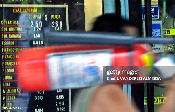 Worker walks infront of sign showing the rate of exchange for foreign currency at a Change Bureau in the financial center of Rio de Janeiro, Brazil,...