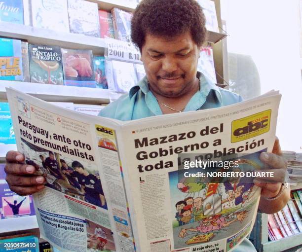 Street salesman reads a newspaper 24 January 2001 in Asuncion, Paraguay, which headlines refer to the rise in many consummer good prices, decreeted...