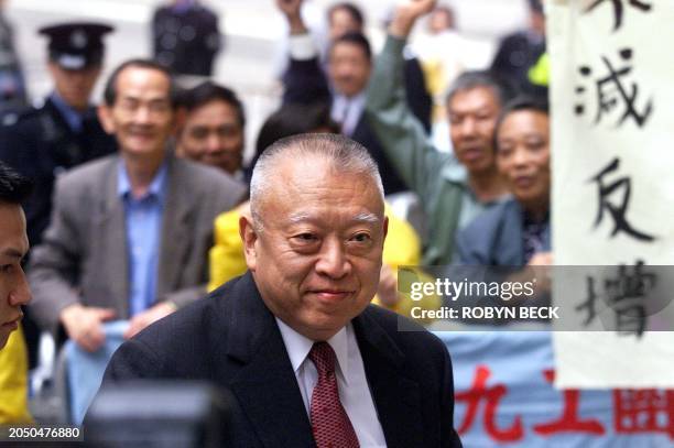 Hong Kong Chief Executive Tung Chee-hwa passes a group of people protesting against any introduction of a sales tax in the territory, 13 January...