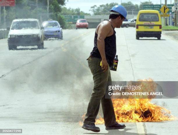 Panamenean construction worker lights a tire to block the main road leading to Tocumen Airport in Panama City 16 December, 1999. The workers...