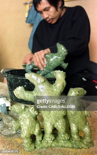 Peter Qumaq sands a soapstone carving in a bucket of water at a school for carvers 29 March, 1999 in Iqaluit, North West Territories, Canada. The...