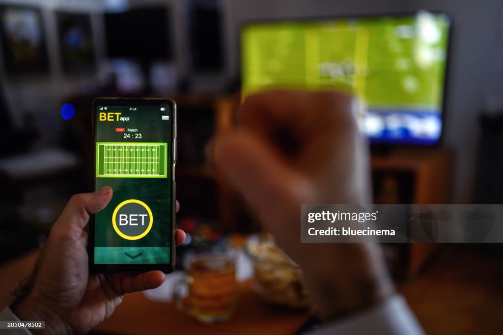 Mature men using smart phone for sports betting.