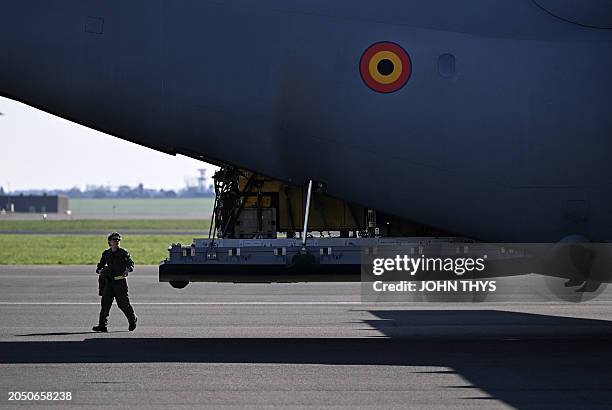 Belgian Air Force soldier walks past a military cargo plane loaded with humanitarian aid, that will be dropped over the Gaza strip, at the military...