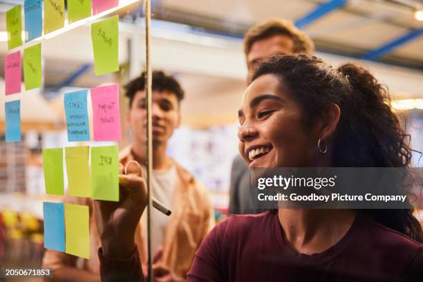 lächelnde gruppe von college-studenten beim brainstorming mit klebenotizen in einer klasse - klebezettel stock-fotos und bilder