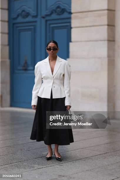 Cherifa Akili seen wearing YSL black sunglasses, silver earrings, Monceau white elegegant blazer jacket, Arket black oversized silk midi skirt, Amina...