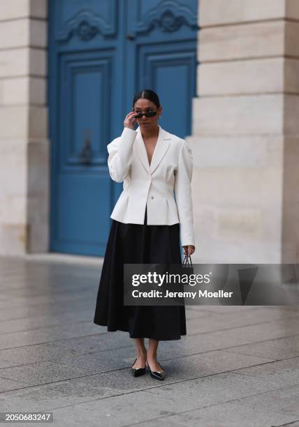 Cherifa Akili seen wearing YSL black sunglasses, silver earrings, Monceau white elegegant blazer jacket, Arket black oversized silk midi skirt, Amina...