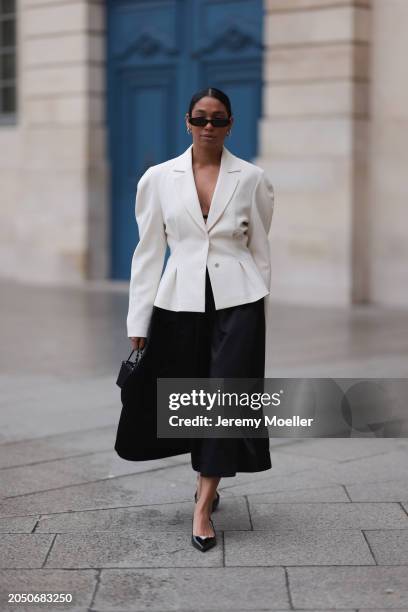 Cherifa Akili seen wearing YSL black sunglasses, silver earrings, Monceau white elegegant blazer jacket, Arket black oversized silk midi skirt, Amina...