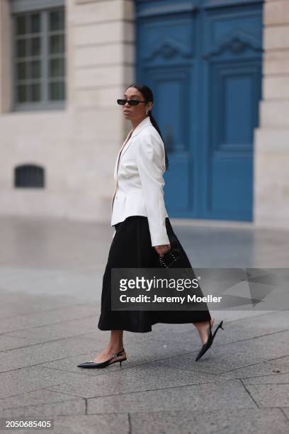 Cherifa Akili seen wearing YSL black sunglasses, silver earrings, Monceau white elegegant blazer jacket, Arket black oversized silk midi skirt, Amina...