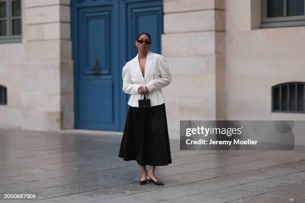 Cherifa Akili seen wearing YSL black sunglasses, silver earrings, Monceau white elegant blazer jacket, Arket black oversized silk midi skirt, Amina...