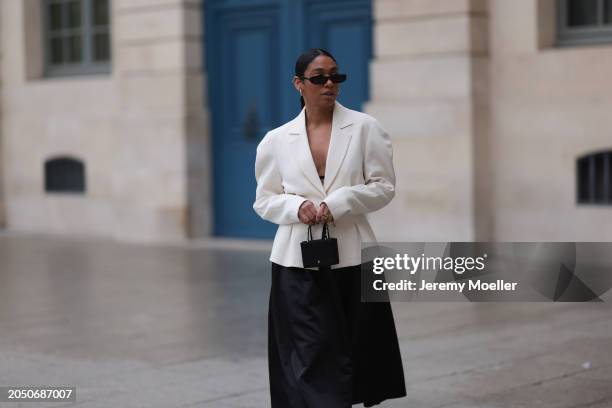 Cherifa Akili seen wearing YSL black sunglasses, silver earrings, Monceau white elegant blazer jacket, Arket black oversized silk midi skirt, Amina...