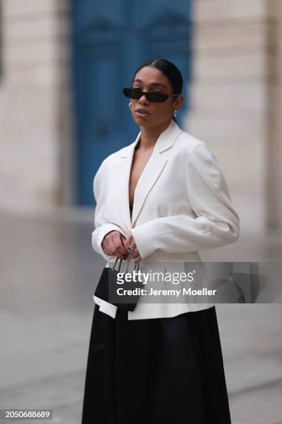 Cherifa Akili seen wearing YSL black sunglasses, silver earrings, Monceau white elegant blazer jacket, Arket black oversized silk midi skirt, Amina...
