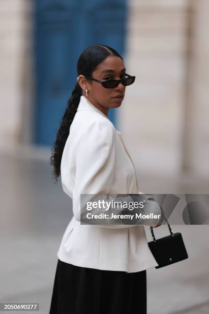 Cherifa Akili seen wearing YSL black sunglasses, silver earrings, Monceau white elegant blazer jacket, Arket black oversized silk midi skirt, Amina...