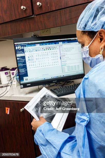 Miami Beach, Florida, Miami Beach Community Health Center, radiology technician, dental office assistant, examining looking at patient x-ray.