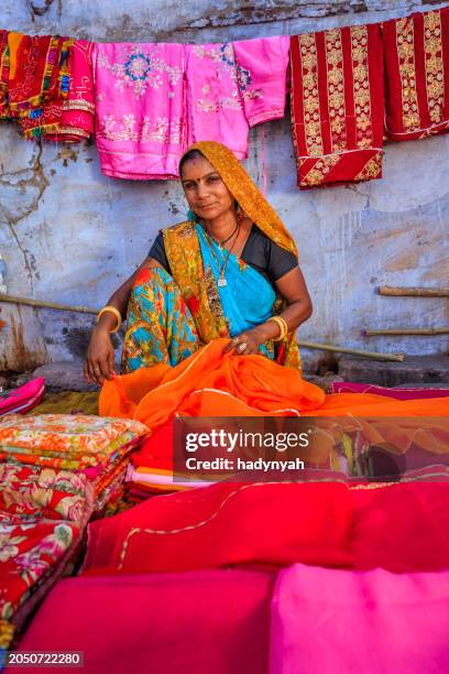 colors of india - woman selling colorful fabrics on local bazaar - sari stock pictures, royalty-free photos & images