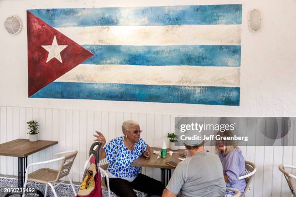 Miami Beach, Florida, Cafe Sazon, Cuban flag with seniors at table.