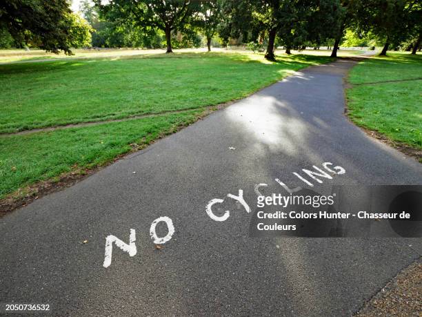 “no cycling” painted on the asphalt of a pedestrian path in hyde park, london, england, united kingdom. 
no people. 
sunlight. natural colors. - forbidden symbol stock pictures, royalty-free photos & images