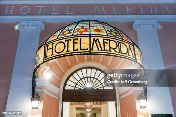 Merida, Mexico, historic district, Calle 60, Hotel Merida stained glass awning marquee lit at night.