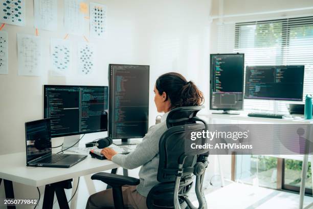 hispanic woman programmer writing code on dual monitors for tech projects - female programmer stock pictures, royalty-free photos & images