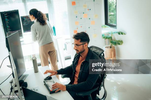 programmatori ispanici che collaborano allo sviluppo di software in un ambiente d'ufficio moderno - programmazione televisiva foto e immagini stock