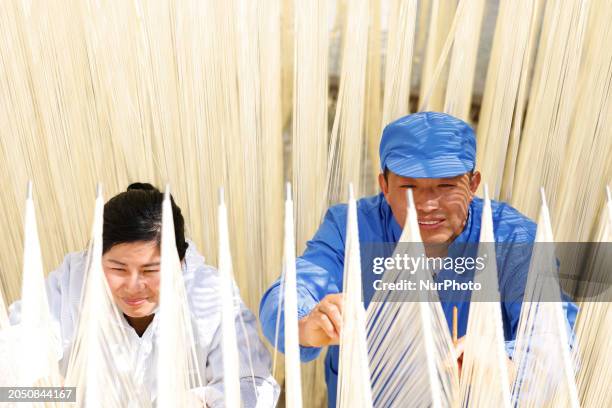 Two workers are processing hollow hanging noodles at a workshop in Suqian, Jiangsu Province, China, on March 3, 2024.